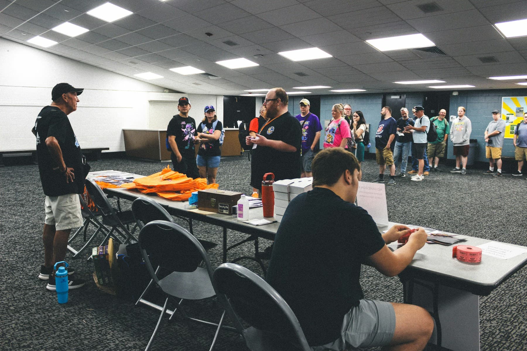 A registration desk with paper lists and a queue of guests waiting